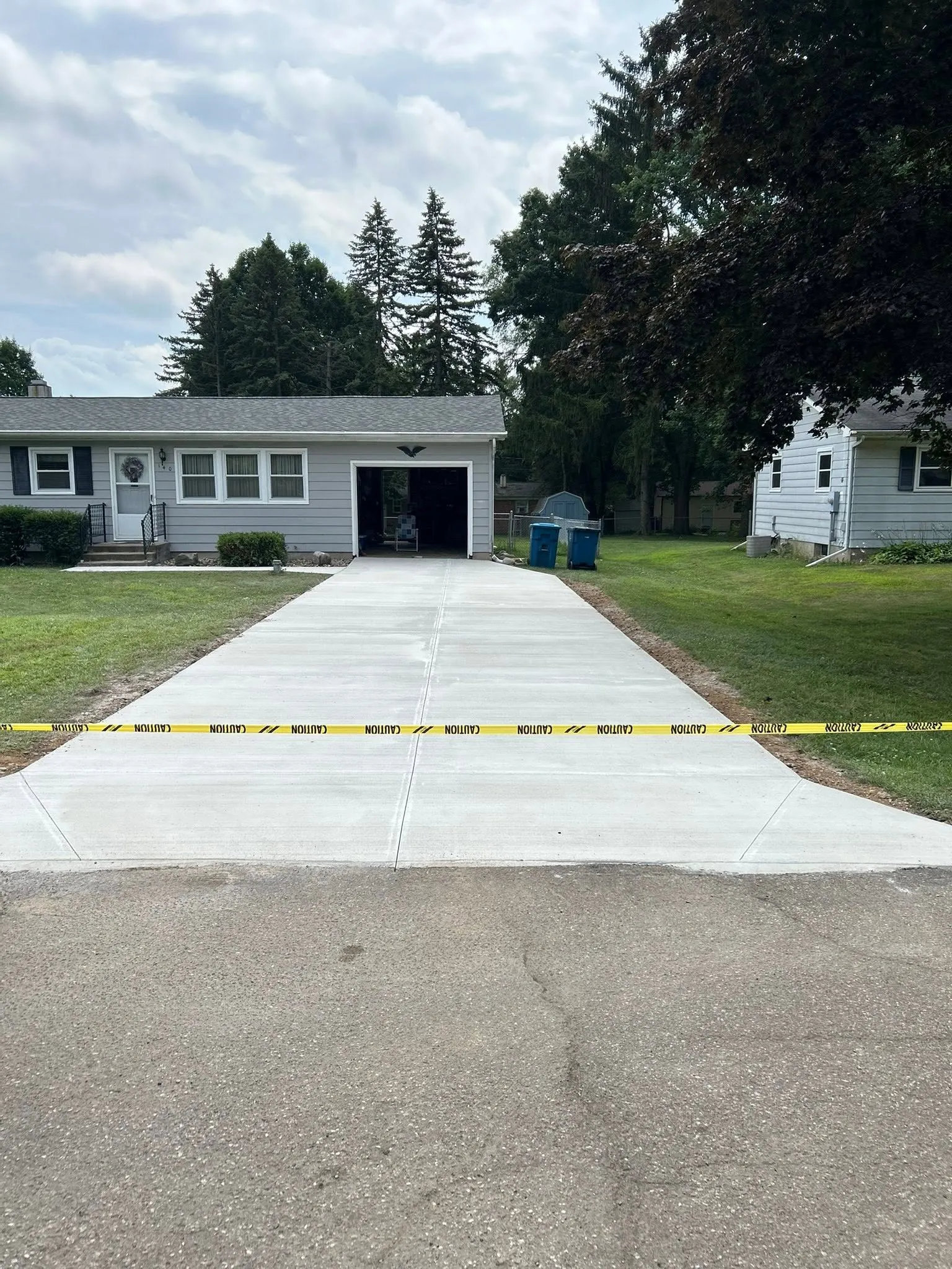 The finished concrete driveway, freshly poured and taped off to cure, running from the street to the attached garage.