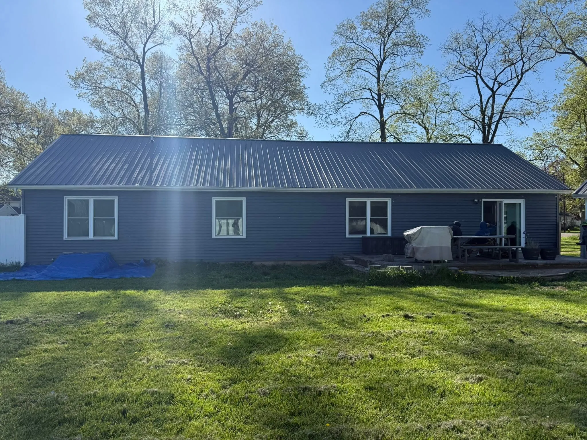 A ranch house with a newly installed dark ribbed metal roof and matching fascia.